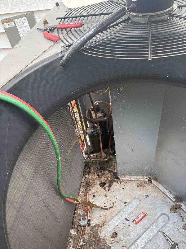 Responded to service call for outdoor unit experiencing short cycling and unusual noises during startup attempts. Upon arrival, performed diagnostic evaluation of 2022 HVAC system. Removed top panel and accessed internal components to inspect compressor, capacitor, electrical connections, and refrigerant lines. Connected manifold gauges to assess refrigerant pressures and system operation. Visual inspection revealed significant debris accumulation in base of unit including dirt, leaves, and organic matter. Examined copper refrigerant lines, electrical wiring connections, and compressor housing for signs of failure or damage. Documented component condition through photography showing weathered copper lines, electrical connections, and internal debris buildup. Tested system operation to replicate reported short cycling condition and identify root cause of startup failure.