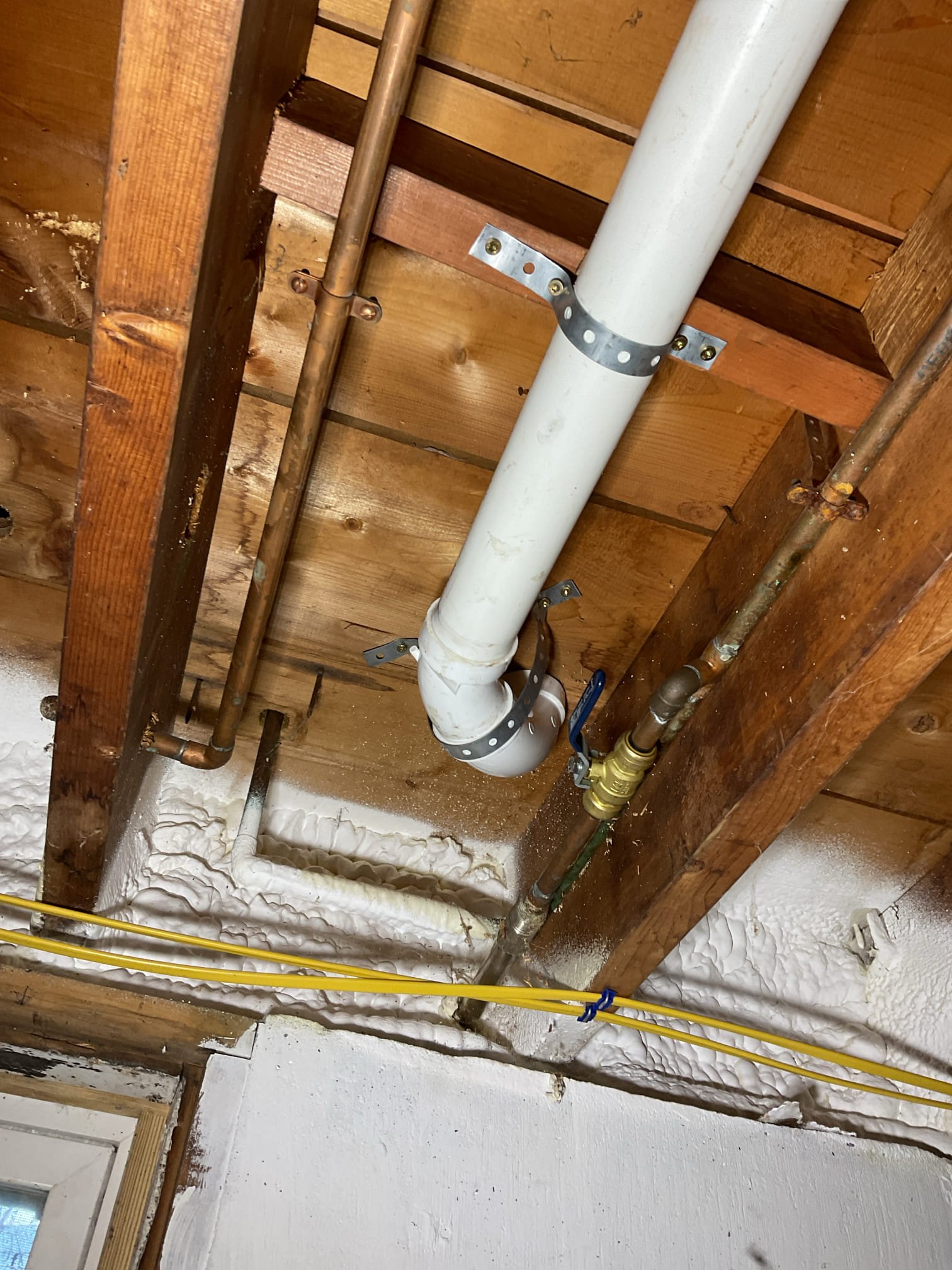 The scope of work included removing the existing copper drainage piping, S-traps, and the right-side basket strainer. We then installed a new 2” PVC drain line from the existing PVC connection to the kitchen sink, maintaining a proper 1/4” per foot slope and securing the piping at 4-foot intervals. We consolidated individual waste lines into a single code-compliant drain and eliminated outdated S-traps. We added a clean-out under the sink where space permitted.
We installed a new shallow-cup basket strainer on the right-side sink using plumber’s putty and tested both sink bays for proper operation with no leaks. We installed a new dishwasher tailpiece with correct pitch to ensure efficient drainage. We installed new plastic tubular end-waste and P-trap assemblies. We installed a new Air Admittance Valve AAV to provide proper venting and improve drainage flow. We cut and properly capped an existing copper drain line—likely serving a dry well—near the tee fitting using a rubber cap to en