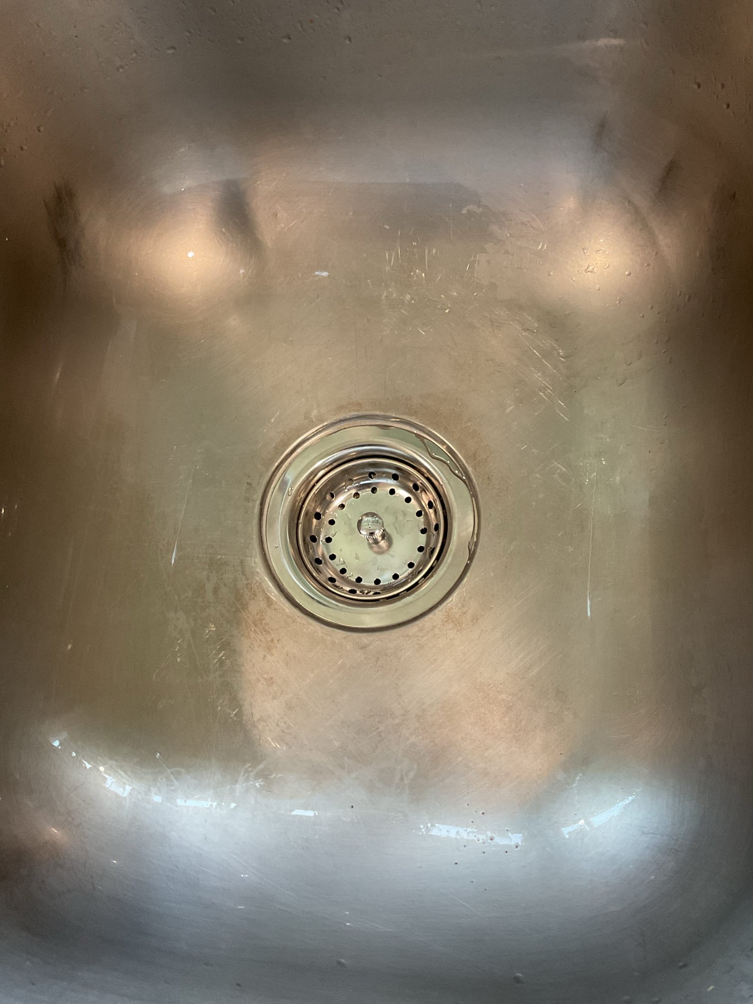 The scope of work included removing the existing copper drainage piping, S-traps, and the right-side basket strainer. We then installed a new 2” PVC drain line from the existing PVC connection to the kitchen sink, maintaining a proper 1/4” per foot slope and securing the piping at 4-foot intervals. We consolidated individual waste lines into a single code-compliant drain and eliminated outdated S-traps. We added a clean-out under the sink where space permitted.
We installed a new shallow-cup basket strainer on the right-side sink using plumber’s putty and tested both sink bays for proper operation with no leaks. We installed a new dishwasher tailpiece with correct pitch to ensure efficient drainage. We installed new plastic tubular end-waste and P-trap assemblies. We installed a new Air Admittance Valve AAV to provide proper venting and improve drainage flow. We cut and properly capped an existing copper drain line—likely serving a dry well—near the tee fitting using a rubber cap to en