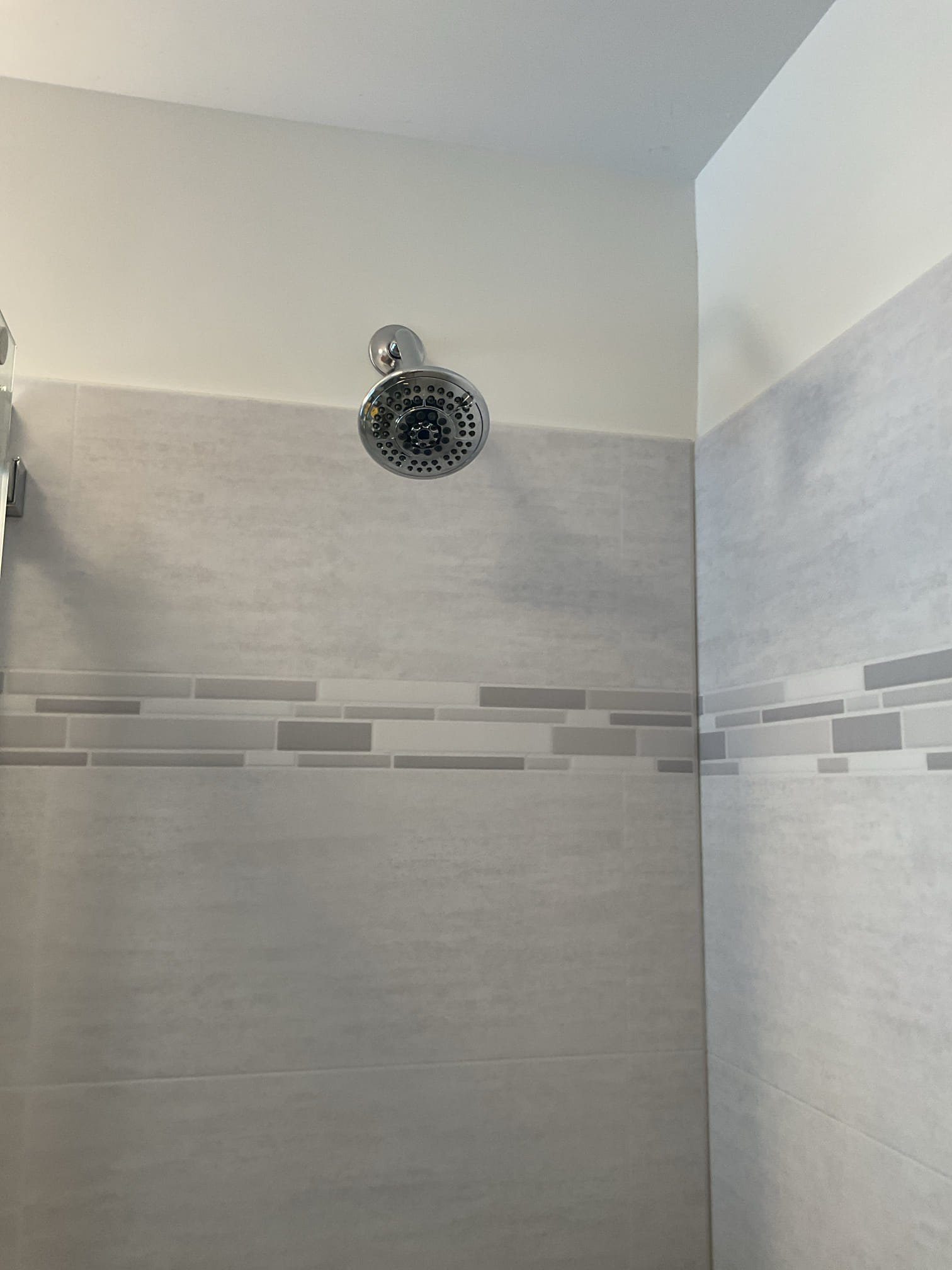 Replaced the shower arm with an 8” long shower arm and applied another layer of sealant along the bottom of the fixed glass panel. 