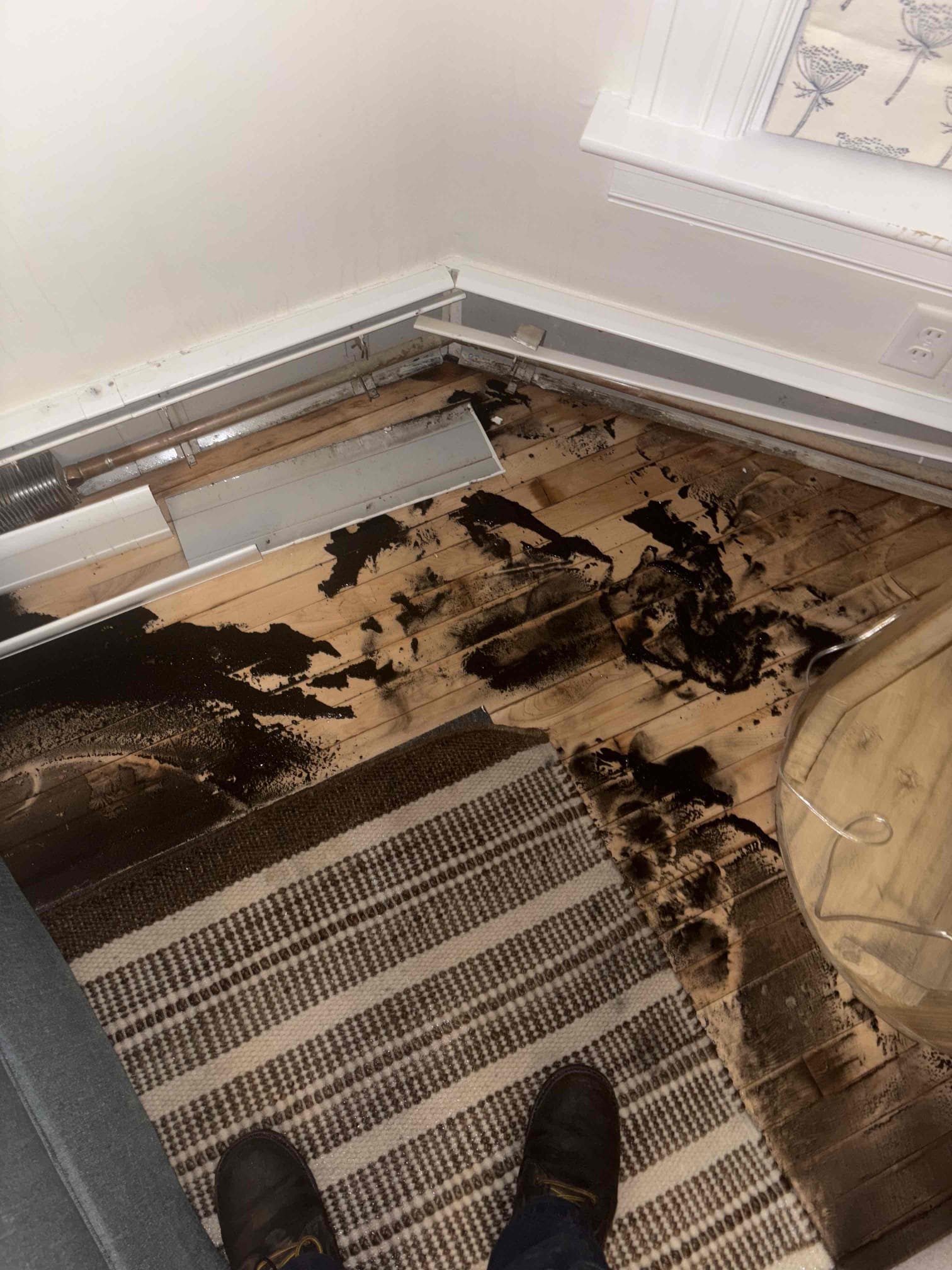 Responded to a report of a leak in the living room and found significant water and black debris around the baseboard. Inspection revealed a hole in the baseboard piping, likely caused by freezing. I isolated the first-floor heating zone and confirmed that the upstairs zone was leak-free and circulating properly, with the upstairs thermostat set to 70 degrees and the first-floor thermostat off. I restored water to the house and verified that no additional leaks were present. Both downstairs mini-split units were turned on and set to 75 degrees in heat mode to maintain temperature. During testing, I found that the first-floor thermostat was intermittently opening and closing the call for heat, indicating a malfunction that may have prevented the zone from heating correctly. We will return shortly to evaluate the necessary repairs.