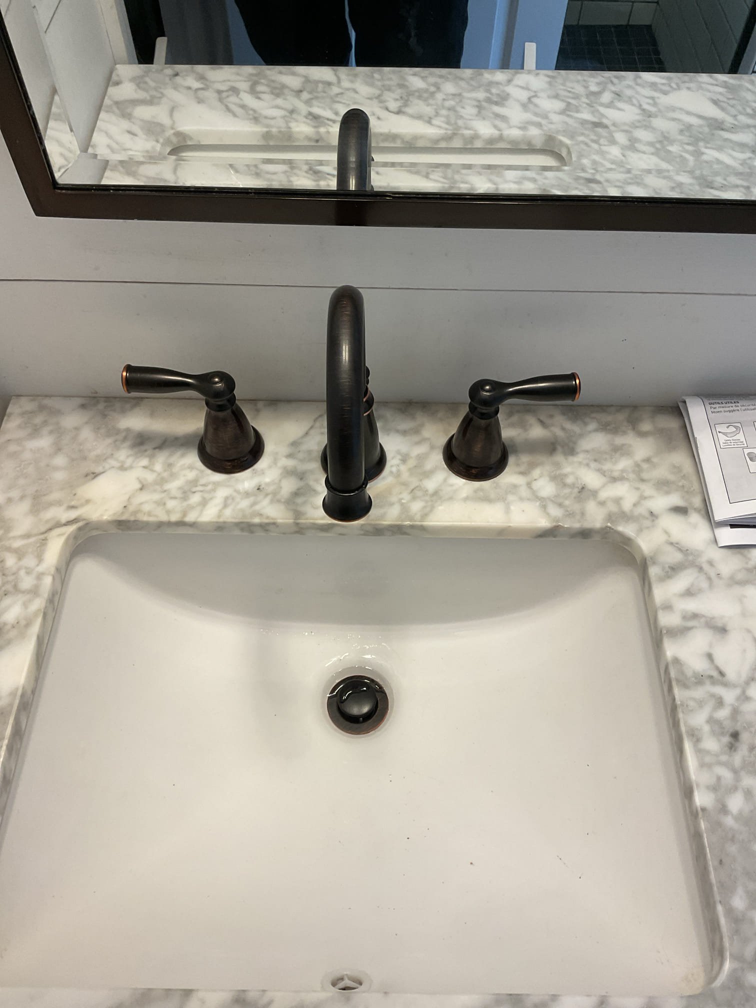 The first-floor lavatory faucet was found to be leaking from the body of the faucet, allowing water to drip into the cabinet below. Due to the internal failure of the faucet, the leak is not repairable and replacement is recommended to prevent further water damage. This estimate includes removal of the existing lavatory faucet and installation of a new, properly fitted replacement faucet once it is ordered and received. All supply connections will be properly secured to current plumbing standards, and the faucet will be tested upon completion to ensure proper operation and that no leaks are present. On 2/16/26, we returned to install the oil-rubbed bronze faucet. The existing faucet was removed and replaced with a new Moen widespread faucet, with all connections properly secured. After installation, the system was tested and verified to be leak-free. We also replaced the existing metal tubular drainage and converted it to new tubular plastic piping, ensuring proper alignment and secure