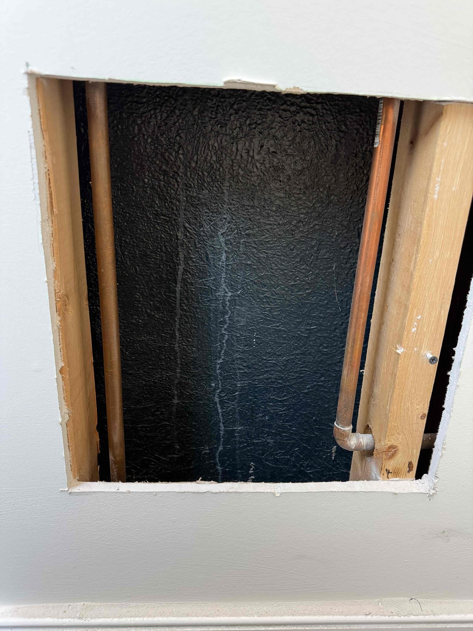 For this job, we responded to inspect a leak reported in the guest bathroom shower. The customer stated that water had been left running while he was away and later noticed water pooling in the kitchen ceiling area directly below the shower. To properly diagnose the issue, an access hole was cut in the bathroom wall to inspect the shower valve and drain assembly. The shower was operated and multiple buckets of water were poured into the base to test the drainage system, and no leaks were found coming from the drain. During inspection, we discovered water leaking from behind the shower valve trim plate. The trim plate was properly sealed with silicone to prevent further water intrusion. We also observed unfinished trim on the exterior edge of the shower, which may have contributed to water escaping the enclosure. Additionally, the kitchen faucet was tightened after noting it was loose. All work was completed, the area was checked for active leaks, and the customer was satisfied with the