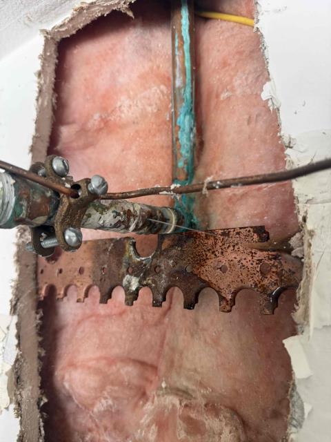 We identified a burst pipe behind the water heater. We shut off the water, removed the damaged section, and prepared for repairs. Access was gained by opening the drywall.