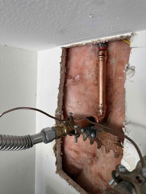 We identified a burst pipe behind the water heater. We shut off the water, removed the damaged section, and prepared for repairs. Access was gained by opening the drywall.