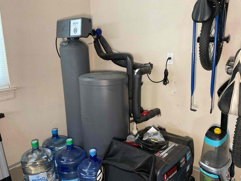 Completed comprehensive plumbing maintenance inspection on 1996 residential property. Evaluated electric tank-style water heater located in attic, documented water softener system and associated equipment in utility area, and performed toilet tank inspection including assessment of flush valve, float mechanisms, and internal components. All systems inspected and photographed for maintenance records.