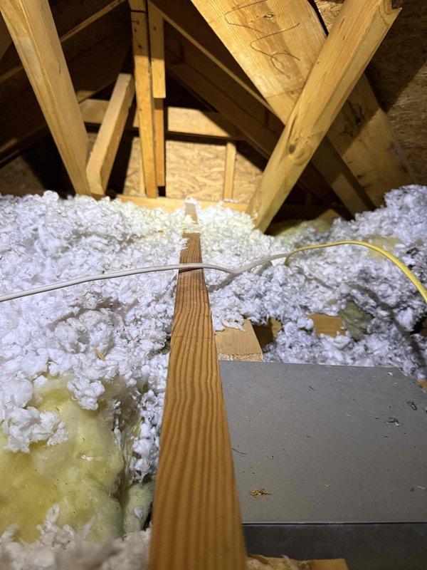 Responded to report that master bathroom exhaust fan was venting into attic space rather than exterior, creating potential fire hazard as identified by pest control. Accessed attic from interior of 29-year-old residence and confirmed exhaust duct was improperly terminated within attic cavity, discharging moisture and lint directly onto insulation. Installed proper rigid ductwork from existing fan housing, routed through attic space to exterior wall penetration, and terminated with weatherproof exterior vent cap to ensure code-compliant ventilation to outside air.