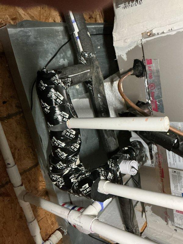 Responded to a not keeping up call at a vacant property with two HVAC systems and a mini-split. Performed diagnostic evaluation on system number two, a nine-year-old unit located in the attic. Inspected air handler, condensate drain pan assembly, and associated refrigerant lines. Verified proper installation of drainage system including PVC condensate lines and overflow pan. Checked routing of refrigerant lines and insulation integrity on copper tubing. Documented system configuration and component conditions through photographic records showing furnace/air handler with coiled flexible duct connections, multiple PVC drain lines with proper pitch and connections, and refrigerant line penetrations through attic space. All mechanical components and piping arrangements were accessible for inspection in the attic installation area.