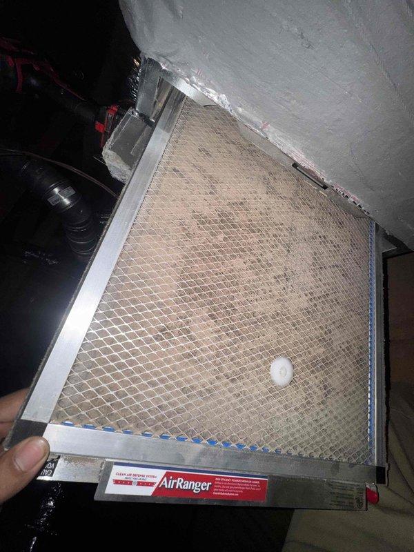 Responded to indoor air quality concern regarding excessive dust accumulation throughout residence with HVAC system less than one year old. Accessed attic-mounted system and inspected air filtration components. Found heavily soiled AirRanger mesh filter with significant dust and debris buildup, consistent with inadequate filtration for residential application. Documented filter condition with photographs showing brownish-tan discoloration across mesh surface and metal frame. Identified filter specifications and provided homeowner with proper replacement filter information for future purchases. Demonstrated filter removal and installation procedure to enable homeowner to perform routine filter changes independently. Recommended establishing regular filter inspection and replacement schedule to improve indoor air quality and reduce dust circulation throughout home.