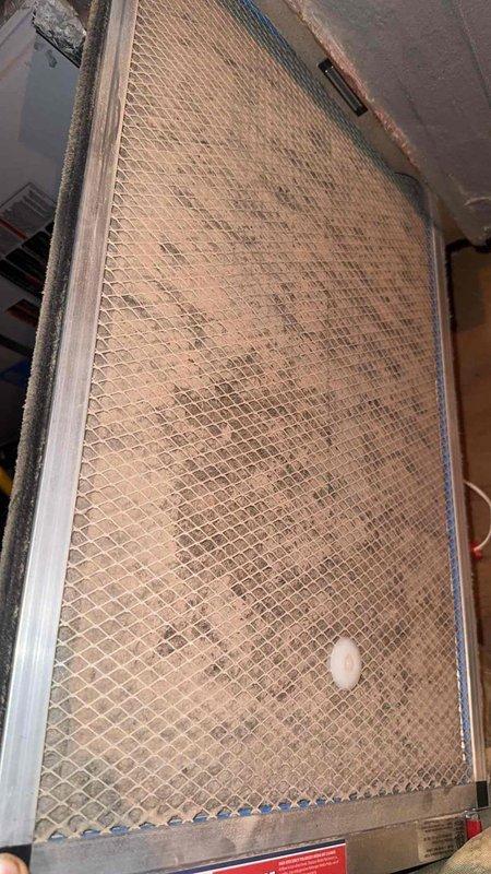 Responded to indoor air quality concern regarding excessive dust accumulation throughout residence with HVAC system less than one year old. Accessed attic-mounted system and inspected air filtration components. Found heavily soiled AirRanger mesh filter with significant dust and debris buildup, consistent with inadequate filtration for residential application. Documented filter condition with photographs showing brownish-tan discoloration across mesh surface and metal frame. Identified filter specifications and provided homeowner with proper replacement filter information for future purchases. Demonstrated filter removal and installation procedure to enable homeowner to perform routine filter changes independently. Recommended establishing regular filter inspection and replacement schedule to improve indoor air quality and reduce dust circulation throughout home.