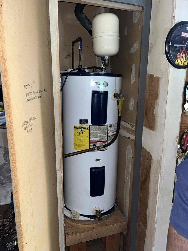 Responded to service call for leaking 11-year-old electric tank water heater located in garage. Upon inspection, confirmed active leak from Whirlpool unit with expansion tank and recirculating system installed. Documented current system configuration including breaker location (#13 on main panel) and photographed equipment condition, noting previous replacement performed in 2015. Provided customer with replacement options and quotes for new water heater installation.
