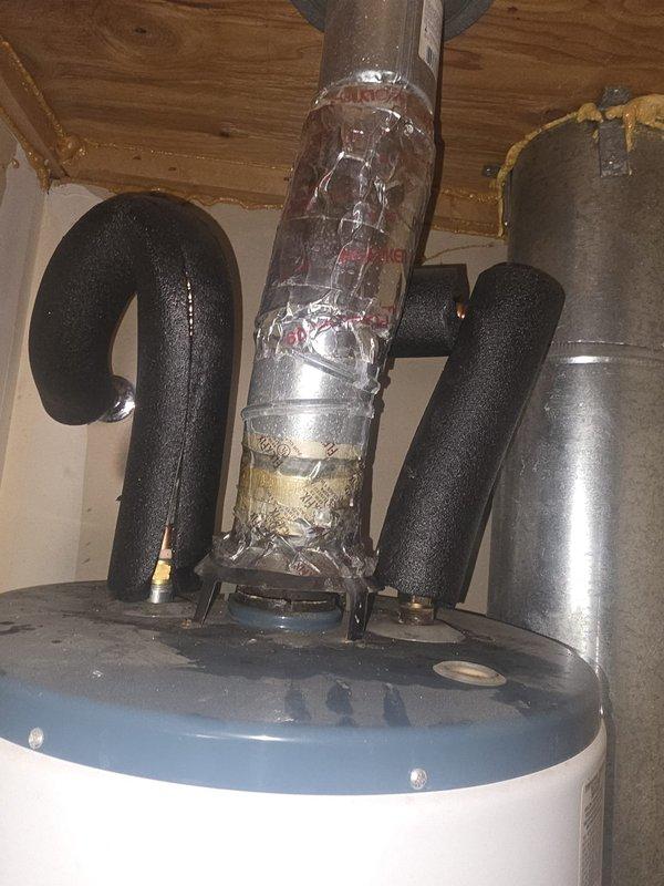 Responded to no hot water emergency at residential property with 20+ year old gas tank water heater actively leaking in garage. Upon inspection, confirmed tank failure with visible water damage on concrete floor beneath unit and compromised tank integrity. Evaluated existing gas line connection with flexible yellow corrugated connector and shut-off valve configuration. Assessed overall plumbing system including overhead pipe routing and insulation condition in utility area. Discussed water heater replacement options and provided consultation on water softener installation to address water quality concerns for the home's plumbing system.