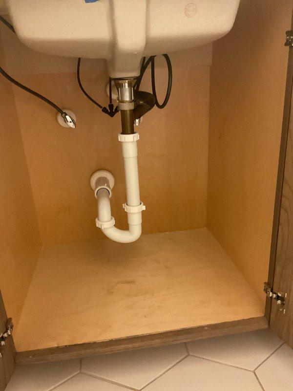 Responded to bathroom sink overflow caused by drain stoppage. Cleared obstruction from P-trap assembly beneath porcelain drop-in sink using mechanical methods. Verified proper drainage flow through PVC waste line and confirmed trap seal integrity. System restored to normal operation with no leaks detected.