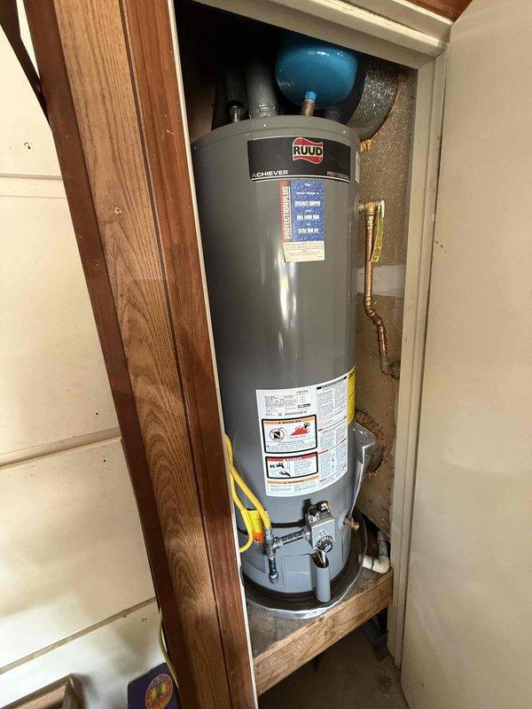 Completed comprehensive plumbing maintenance on 32-year-old residential property with 2,000 square feet. Inspected and serviced 11-month-old Ruud Achiever gas tank water heater located in garage, previously installed by our company in August 2025. Verified proper operation of all water heater components including temperature and pressure relief valve, gas connections with yellow flexible gas line, brass piping connections at top of unit, and blue pressure tank mounted above unit. Checked water heater for signs of leaks, corrosion, or sediment buildup. Inspected flexible braided metal water supply lines and gray corrugated flexible conduit at ceiling access point. Verified proper operation of shut-off valves including blue valve handles at ceiling access panel. Tested temperature settings and confirmed unit is heating efficiently. Inspected all visible plumbing connections throughout accessible areas of home. All components found to be functioning properly with no leaks detected. System