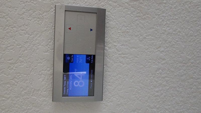 Responded to return service call for recurring system issue. Upon arrival, found thermostat displaying "Call For Service" alert with outside temperature reading 106°F and system struggling to maintain cooling setpoint of 74°F while indoor temperature had risen to 86°F. Documented thermostat error conditions and system performance indicators showing unit operating in cooling mode with auto fan setting but failing to adequately cool structure during extreme ambient conditions. Captured diagnostic images of thermostat display and alert status for further analysis and follow-up troubleshooting of underlying system malfunction.