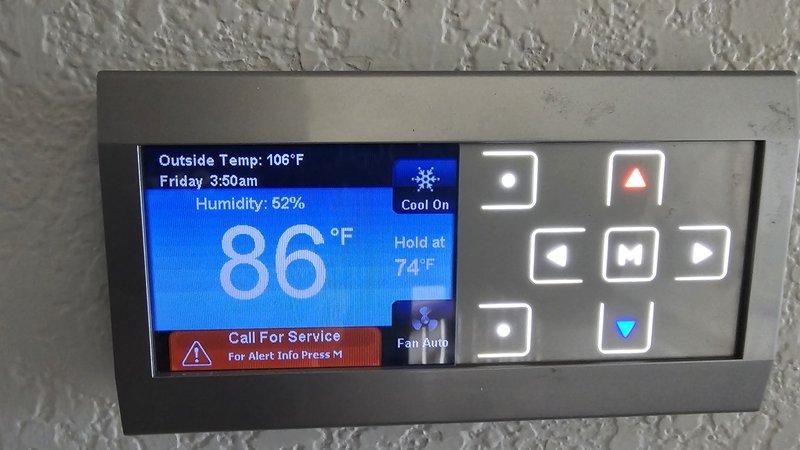 Responded to return service call for recurring system issue. Upon arrival, found thermostat displaying "Call For Service" alert with outside temperature reading 106°F and system struggling to maintain cooling setpoint of 74°F while indoor temperature had risen to 86°F. Documented thermostat error conditions and system performance indicators showing unit operating in cooling mode with auto fan setting but failing to adequately cool structure during extreme ambient conditions. Captured diagnostic images of thermostat display and alert status for further analysis and follow-up troubleshooting of underlying system malfunction.
