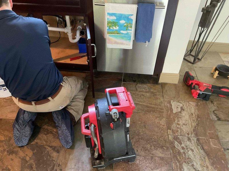 Responded to clogged kitchen sink in 1980s residence. Upon arrival, confirmed complete drainage blockage in stainless steel basin. Deployed professional drain cleaning equipment and accessed P-trap assembly beneath cabinet. Cleared obstruction from drain line using mechanical auger, restoring full water flow and proper drainage. Tested system to verify complete resolution and left work area clean.