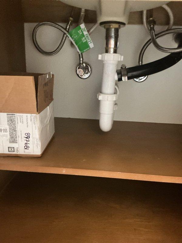 Responded to clogged bathroom sink in 1992 home. Upon inspection, found undermount white rectangular basin with bronze pop-up drain assembly and three-handle faucet fixture experiencing drainage issues. Accessed plumbing beneath sink and cleared obstruction from P-trap assembly. Verified proper drainage flow through tailpiece and trap configuration. Tested sink operation and confirmed water drains freely with no backup or slow drainage remaining.