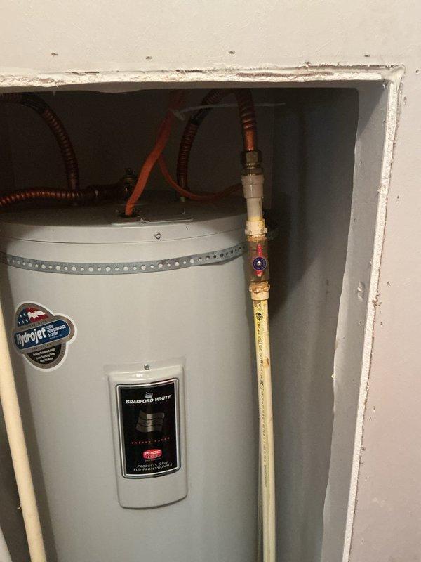 Performed water heater flush service on electric tank-type water heater located in bedroom closet. Unit is over 10 years old and showing signs of age with visible corrosion on brass fittings and pressure relief components. Completed standard flush procedure, inspected all plumbing connections at top of unit including hot and cold supply lines, temperature/pressure relief valve, and associated piping, and documented current condition of system for homeowner's records.