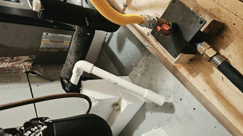 Responded to service call for 3-year-old residential HVAC system in attic not cooling and failing to maintain temperature. Accessed attic system using gate code, confirmed safe working conditions. Inspected air handling unit, condensate drain pan, drainage lines, and associated ductwork. Documented system condition including condensate management components, PVC drainage piping with brass fittings and shut-off valve, and flexible ductwork connections. Evaluated unit operation, checked refrigerant levels, and assessed airflow through silver flex duct system. System restored to proper cooling operation and temperature holding capability.