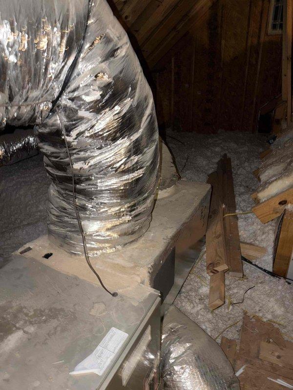 Responded to no cooling complaint on 11-year-old residential AC system. Upon arrival, confirmed thermostat set to 75°F but indoor temperature reading 80°F with unit running continuously. Accessed attic-mounted air handler and inspected system components. Found significant damage to flexible supply ductwork with multiple tears in outer metallic vapor barrier exposing inner insulation layer, resulting in substantial conditioned air loss into unconditioned attic space. Performed electrical diagnostics at outdoor condensing unit using clamp meter, measuring 11.18 amps draw on compressor circuit with system operating. Readings indicate compressor functioning within normal parameters. Primary issue identified as compromised ductwork integrity preventing adequate airflow delivery to conditioned spaces. Recommended immediate duct repair or replacement to restore system cooling capacity and efficiency. Documented conditions with photographs showing extent of duct damage and electrical measureme