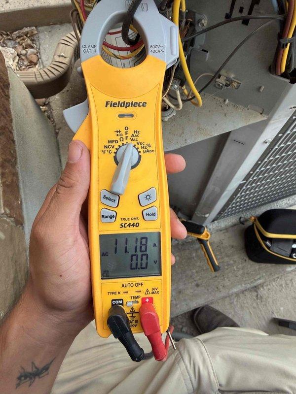 Responded to no cooling complaint on 11-year-old residential AC system. Upon arrival, confirmed thermostat set to 75°F but indoor temperature reading 80°F with unit running continuously. Accessed attic-mounted air handler and inspected system components. Found significant damage to flexible supply ductwork with multiple tears in outer metallic vapor barrier exposing inner insulation layer, resulting in substantial conditioned air loss into unconditioned attic space. Performed electrical diagnostics at outdoor condensing unit using clamp meter, measuring 11.18 amps draw on compressor circuit with system operating. Readings indicate compressor functioning within normal parameters. Primary issue identified as compromised ductwork integrity preventing adequate airflow delivery to conditioned spaces. Recommended immediate duct repair or replacement to restore system cooling capacity and efficiency. Documented conditions with photographs showing extent of duct damage and electrical measureme