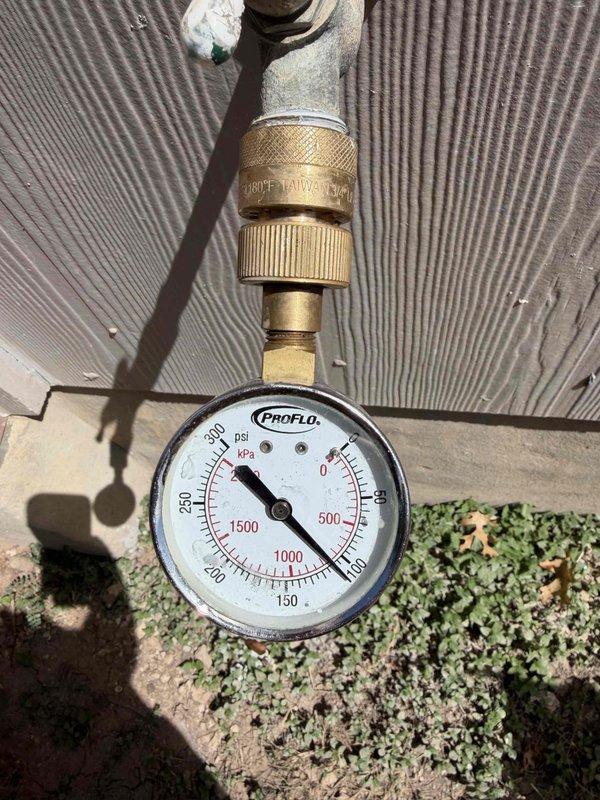 Responded to service request for pressure reducing valve (PRV) inspection at 2,380 sq ft residential property built in 2006. Located and accessed ground-level valve box in lawn area, which contained PRV assembly with visible signs of age, corrosion, and soil accumulation on valve body and fittings. Removed irrigation system riser components and access covers to gain full access to valve assembly. Connected calibrated pressure gauge to test ports on PRV system using brass fittings and quick-connect couplings. Measured and recorded static water pressure readings using ProFlo dial gauge to verify valve operation and downstream pressure regulation. Valve assembly showed weathering consistent with underground utility infrastructure exposure. Documented valve condition, pressure readings, and overall system status with photographic evidence. Valve box and surrounding components exhibited corrosion on metal surfaces and dirt accumulation from years of service. This represented the first plumb