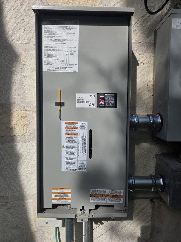 Completed scheduled maintenance on air-cooled standby generator unit located at front side of residence. Performed comprehensive system inspection including visual examination of all external components, control panel functionality check, and verification of utility disconnect operation. Replaced backup battery as part of routine maintenance cycle per manufacturer specifications. Inspected electrical connections at transfer switch and disconnect box, confirming all warning labels and safety placards present and legible. Verified proper mounting and secure positioning of unit on prepared pad with gravel base. Checked flexible conduit connections and confirmed no signs of corrosion or damage to enclosure panels. System tested and operating within normal parameters with no issues reported by homeowner prior to service visit.