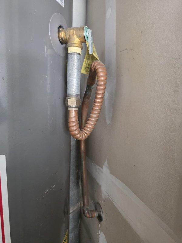 Performed preventive maintenance flush on 5-year-old gas tank water heater at 1997-built residential property. Drained sediment buildup from tank bottom through drain valve, flushed system with fresh water to remove mineral deposits and debris, and verified proper operation of temperature/pressure relief valve. Inspected gas supply line connections including brass shut-off valve and flexible copper connector for leaks and proper installation, confirmed secure mounting and code-compliant configuration. Examined pipe penetrations and insulation integrity at mechanical connections, noting existing insulation condition around ductwork pass-throughs. All components tested and returned to normal operation with no leaks detected upon completion of flush procedure.