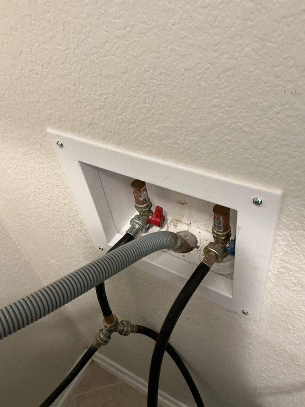 Responded to emergency water leak in laundry room of 14-year-old residence. Upon arrival, inspected washing machine supply connections housed in recessed wall outlet box and identified faulty shut-off valve causing active leak. Replaced defective valve assembly, installed new braided stainless steel supply lines with proper hot and cold connections, and tested water quality to ensure system integrity. Verified all connections were secure with no leaks present upon completion.