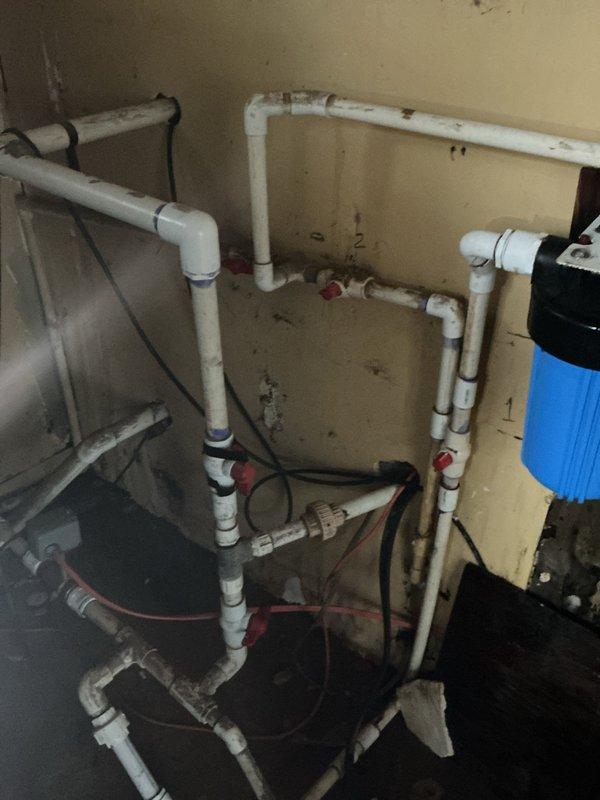 Responded to active leak on GE water heater. Upon arrival, inspected unit and water supply connections at top of heater where flexible braided supply lines connect to domestic water system. Identified source of leak and performed necessary repairs to stop water discharge. Verified all connections at water heater, including hot and cold supply lines with red and blue fittings, were properly secured. Inspected associated plumbing system including PVC piping configuration with multiple shut-off valves and blue water filter housing to ensure no additional leaks present. Tested system operation and confirmed leak was resolved with no further water discharge observed.