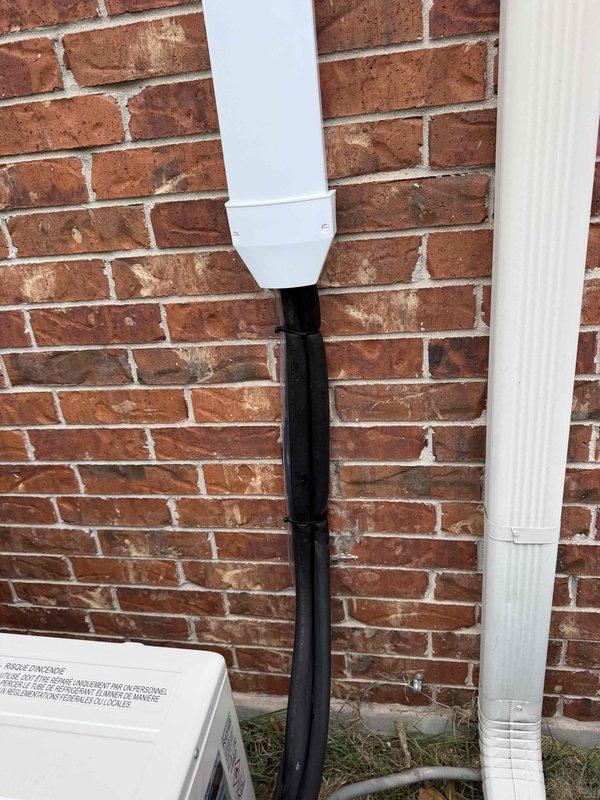 Completed installation of new 18,000 BTU Mitsubishi mini-split system on residential brick and vinyl siding exterior. Mounted outdoor condenser unit at ground level, installed refrigerant line set and electrical disconnect box on exterior wall, and routed condensate drainage through white PVC piping along brick facade. System includes comprehensive 12-year parts and labor warranty coverage.