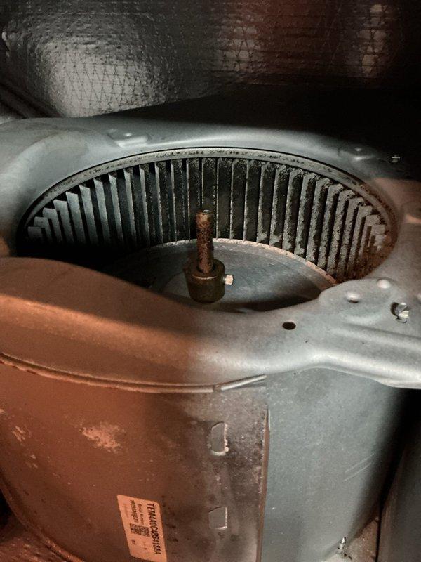 Responded to emergency drain issue at residential property with 3,155 square foot home containing approximately 5-year-old HVAC system. Upon inspection, discovered extensive ice accumulation on evaporator coils and internal components of air handler unit located in attic space. Heavy frost buildup observed throughout coil surfaces indicating restricted airflow and potential drainage complications. Blower motor assembly exhibited significant dust and debris accumulation on wheel fins and internal surfaces, contributing to reduced system efficiency and airflow restriction. Documented moisture staining and condensation on cylindrical blower housing and surrounding drain lines. Photographed frozen evaporator coils and contaminated blower assembly for records. System required immediate attention to address ice formation, clear drain blockage, and restore proper operation. Recommended thorough cleaning of blower assembly and evaluation of drain line functionality once system defrosted.