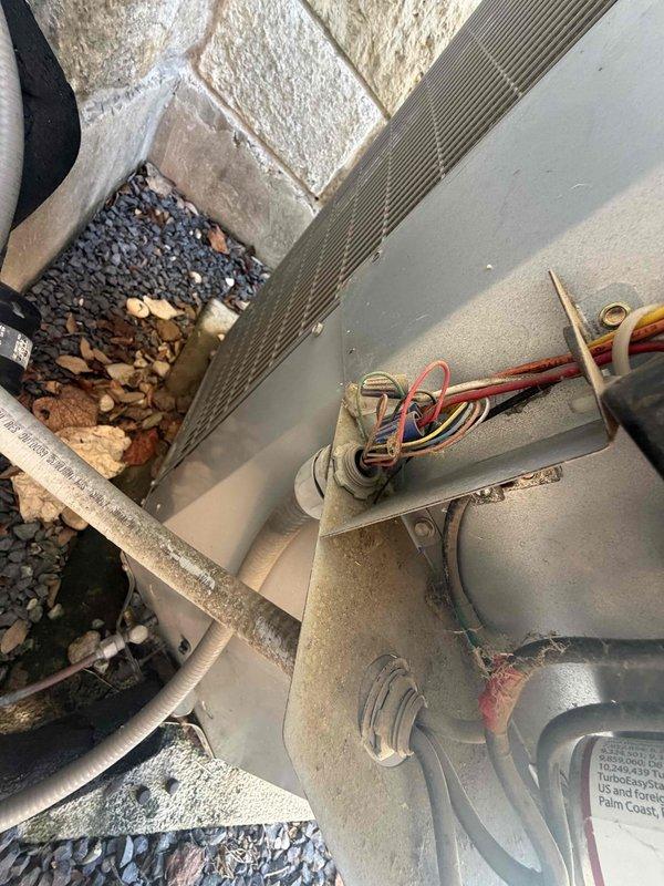 Responded to service call for 12-year-old central HVAC system not cooling with audible struggling sounds from attic unit. Accessed attic space via garage pull-down ladder to inspect air handler and assessed outdoor condensing unit for operational issues. Diagnosed system malfunction, inspected electrical connections and wiring at condenser, and evaluated overall unit condition showing age-related wear and debris accumulation requiring attention.