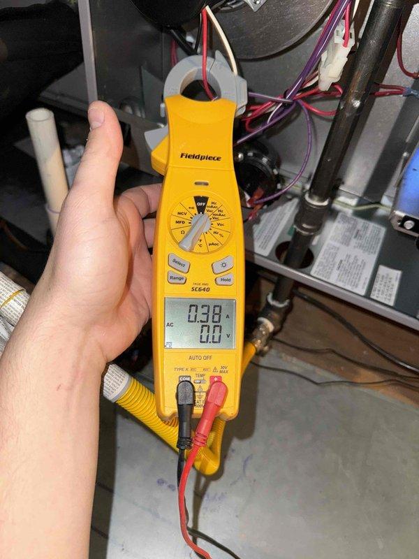 Performed member maintenance inspection on the attic-mounted HVAC system, including electrical measurements at the air handler (blower motor amp draw recorded at 0.38 A) and verification of gas line, PVC condensate drain, and wiring connections with no frost, ice, rust, or visible damage observed. Inspected attic ductwork and identified torn and peeled foil-faced insulation on the rectangular duct board, exposing fiberglass insulation; surface temperature of approximately 104°F was measured at the duct, and the damaged insulation facing is recommended for repair to restore thermal and vapor barrier integrity.
