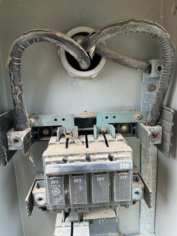 Inspected the main service equipment and distribution panel in response to outlet concerns and a request for a generator inlet. Found the service disconnect and panel interior heavily soiled with dust and debris, with cracked, weathered conductor insulation on the main feeder cables and oxidation on the bus bar lugs and mounting hardware. The Square D distribution panel showed aged, loosely arranged branch wiring. Documented all conditions photographically and evaluated the system's suitability for a generator inlet installation, which will require remediation of the deteriorated feeder conductors and terminations prior to any added equipment.