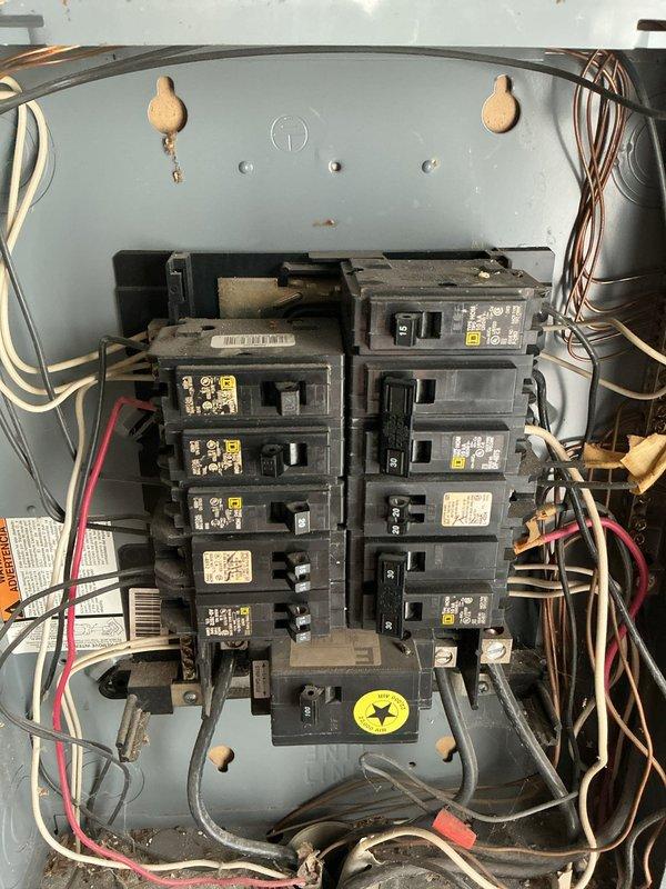 Inspected the main service equipment and distribution panel in response to outlet concerns and a request for a generator inlet. Found the service disconnect and panel interior heavily soiled with dust and debris, with cracked, weathered conductor insulation on the main feeder cables and oxidation on the bus bar lugs and mounting hardware. The Square D distribution panel showed aged, loosely arranged branch wiring. Documented all conditions photographically and evaluated the system's suitability for a generator inlet installation, which will require remediation of the deteriorated feeder conductors and terminations prior to any added equipment.