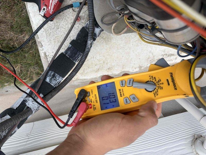 Performed a member maintenance inspection on a 6-year-old split system with an attic-mounted air handler and outdoor condenser. Inspected the condenser coil and guard grille, finding no frost, rust, or visible damage, and measured ambient air temperature at the condenser. Used a clamp meter to check electrical operation of the outdoor unit, including amperage draw at the wiring and capacitor/motor section, and verified the line-set conduit and wiring connections were intact.