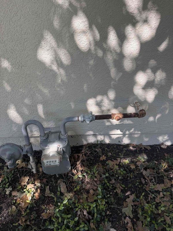 Responded to a reported strong natural gas odor near the meter and inspected the meter assembly and surrounding piping. Observed heavy corrosion on the horizontal supply line downstream of the meter, particularly at the union and elbow fitting, identifying these as potential leak points. Also checked the adjacent interior cabinet stub-out, which showed no visible damage or anomalies; the corroded exterior gas piping is recommended for repair or replacement.