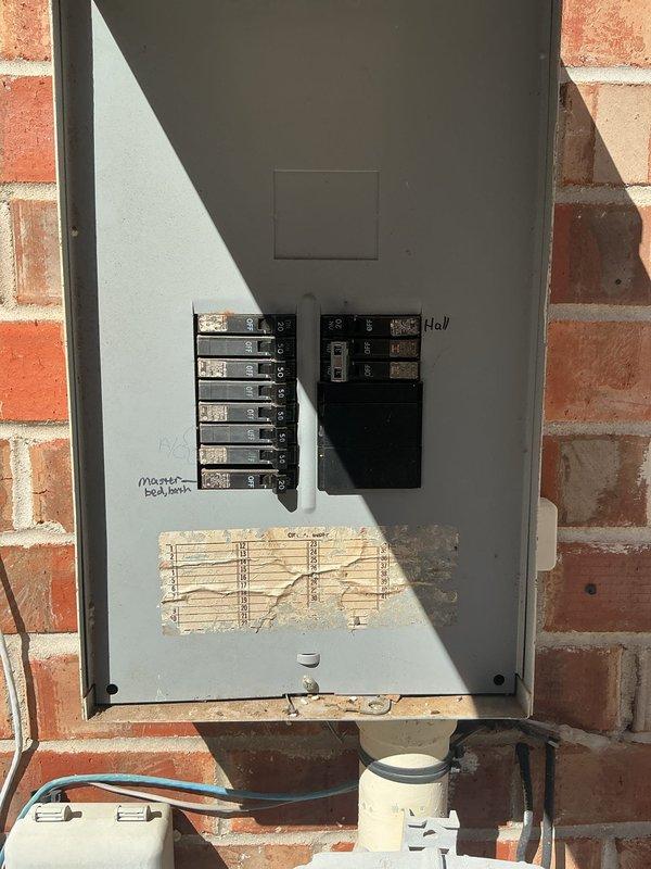 Inspected the exterior electrical panel in response to reported nonfunctioning garage GFCI and outdoor lighting circuits and concerns of overload from added aquarium and landscape lighting loads. Found the enclosure contaminated with dried mud dauber nests, debris, and dried vine growth around the conductors and terminations, with the circuit directory deteriorated and illegible, and several breakers in the OFF position. Documented panel conditions and breaker labeling, and noted the need for enclosure cleaning, circuit directory replacement, and load evaluation of the affected circuits.