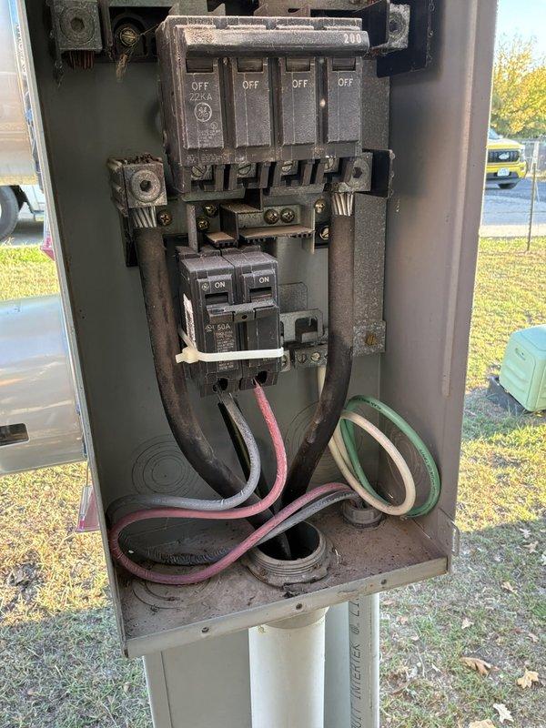 Performed a site evaluation for a whole-home standby generator installation, inspecting the existing outdoor pedestal-mounted electrical enclosure containing the main breaker panel and 50A two-pole breaker, and documenting the dual-meter Milbank enclosure with Oncor Focus AXR-SD meters. Photographed the service equipment, conduit entry, and surrounding area to determine generator placement, transfer switch integration, and service entrance requirements, noting the dusty enclosure interior and the existing wiring configuration for the quote.