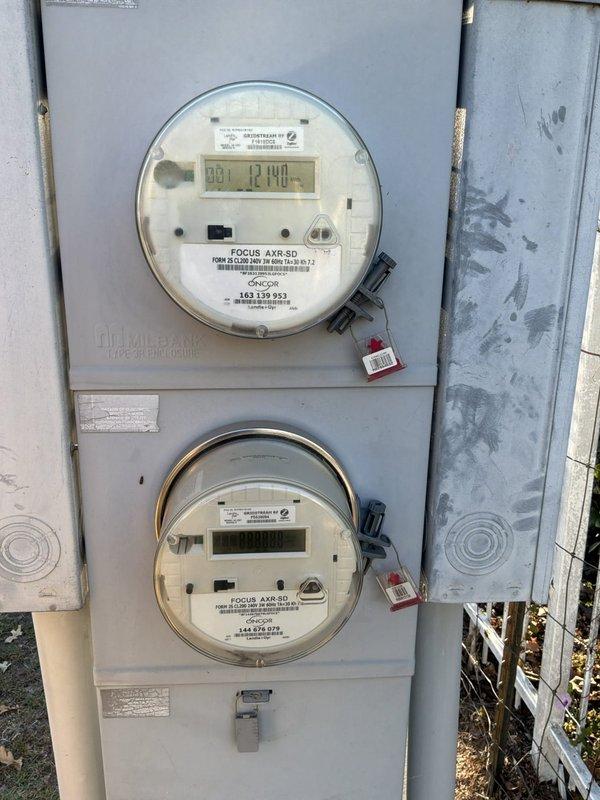 Performed a site evaluation for a whole-home standby generator installation, inspecting the existing outdoor pedestal-mounted electrical enclosure containing the main breaker panel and 50A two-pole breaker, and documenting the dual-meter Milbank enclosure with Oncor Focus AXR-SD meters. Photographed the service equipment, conduit entry, and surrounding area to determine generator placement, transfer switch integration, and service entrance requirements, noting the dusty enclosure interior and the existing wiring configuration for the quote.