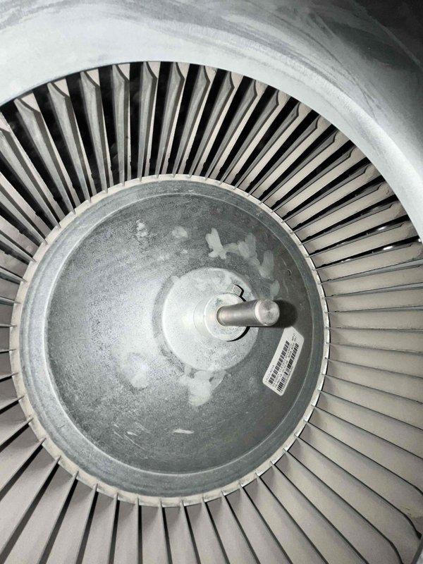 Performed seasonal preventive maintenance on a single-zone split system with an attic-mounted air handler. Inspected the blower assembly and found the squirrel-cage wheel and housing coated in light dust, with mineral deposits or corrosion residue on the wheel's galvanized hub plate, and inspected the lined supply plenum and trunk, which showed matted insulation with minor loose fibers and debris. The system is under one year old and no operational deficiencies were noted, though blower wheel cleaning and continued monitoring of the residue are recommended.