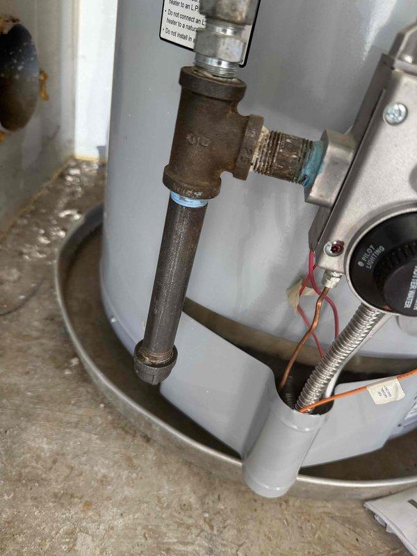 Performed a water heater flush on a two-year-old gas-fired tank unit in the garage and completed a multi-point plumbing system inspection covering fixtures, supply and drain piping, and the water heater. Inspection identified surface rust, corrosion, and mineral buildup on the black iron gas piping and threaded joints at the base of the water heater, with moisture and staining present in the drain pan and on the surrounding floor. Documented findings with photos and reviewed the completed inspection checklist with the customer for follow-up recommendations.