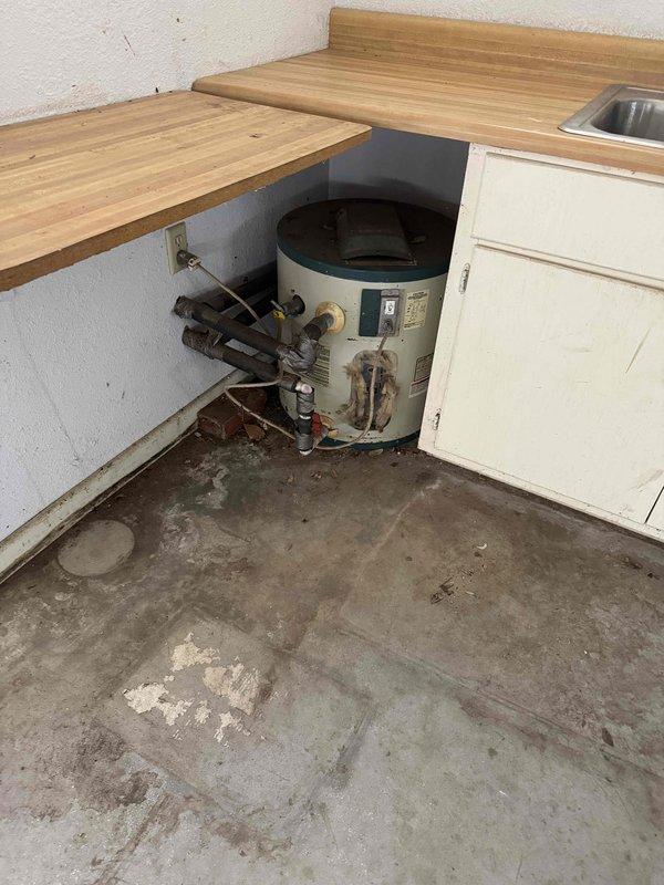 Responded to a leak at the washer connection in the middle bathroom and isolated it by shutting off the water supply to stop the leak. Documented the gas water heater (Rheem Classic Series, installed in a drain pan, handwritten install date on tank) and an electric point-of-use water heater under a countertop, recording system condition for the property's service history.