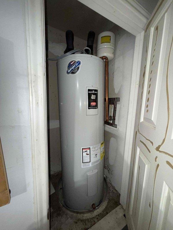 Performed a water heater flush on the 5-year-old electric tank unit and evaluated the primary bathroom's low water pressure complaint. Inspected the shower valve trim and found heavy scratching, mineral buildup, and corrosion on the escutcheon plate, indicating wear and possible scale restriction at the valve. Also noted staining and grime at the water heater base and closet floor pan, with the thermal expansion tank in place, and recommended continued annual maintenance to protect the heater and maintain system performance.