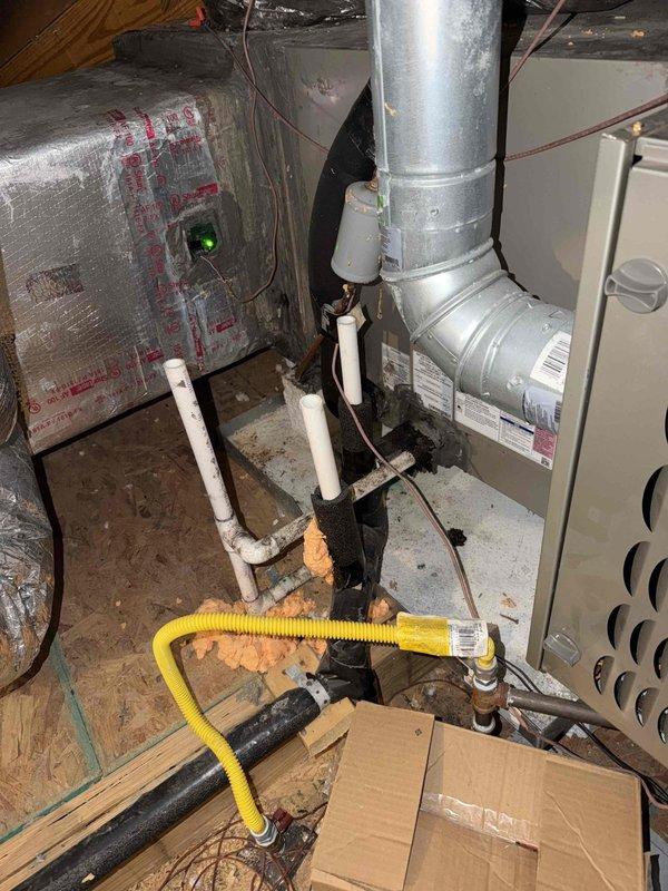 Responded to a no-operation call on a 6-year-old split system with the furnace and air handler located in the attic. Inspected the furnace area and found dark soot-like staining and charring on the foam-insulated line at the furnace base, along with debris and spray foam residue around the condensate and PVC piping. Performed electrical diagnostics at the outdoor condenser using a true RMS clamp meter, measuring amperage draw at the electrical compartment and inspecting the run capacitor and associated wiring. Documented findings with photos for review and follow-up recommendations.