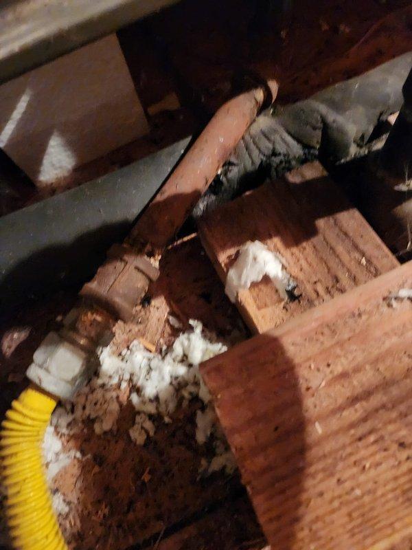 Performed seasonal maintenance on the attic-mounted split system, including inspection of the air handler and removal of a heavily soiled fiberglass return air filter, which was restricting airflow. Inspected the surrounding attic equipment area and noted a corroded gas line fitting with a flexible gas connector, as well as torn, deteriorated duct or pipe insulation, both of which should be evaluated and repaired to prevent efficiency loss and safety concerns.