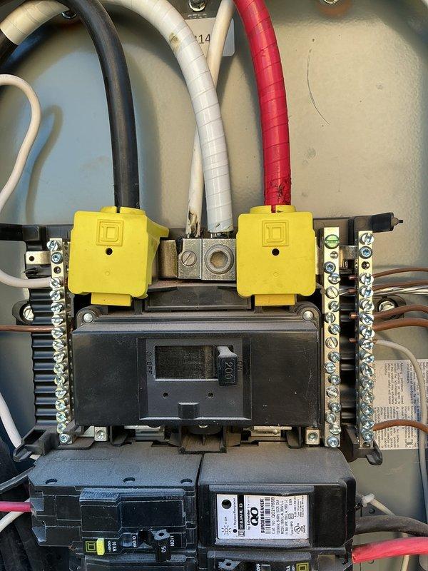 Inspected the main electrical panel (Square D, 200A main breaker) to evaluate power availability for a customer-supplied Google Nest floodlight camera at the rear/side exterior of the home. Verified the main breaker and installed Square D QO surge protection breaker, and observed discoloration near the white conductor termination at the main lug that warrants further evaluation. Documented panel conditions, including available breaker capacity and blanking plates covering unused positions, to support planning of the exterior camera circuit installation.