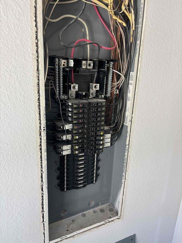 Evaluated the electrical service for the requested exterior garage light installation, including inspection of the main breaker panel with the cover removed and the exterior service entrance equipment (meter base, disconnect enclosure, conduit, and telecommunications box) to assess available capacity and routing for the new circuit. The panel and exterior equipment were documented with photos, with no major damage noted, and the installation scope was reviewed for the exterior lighting.